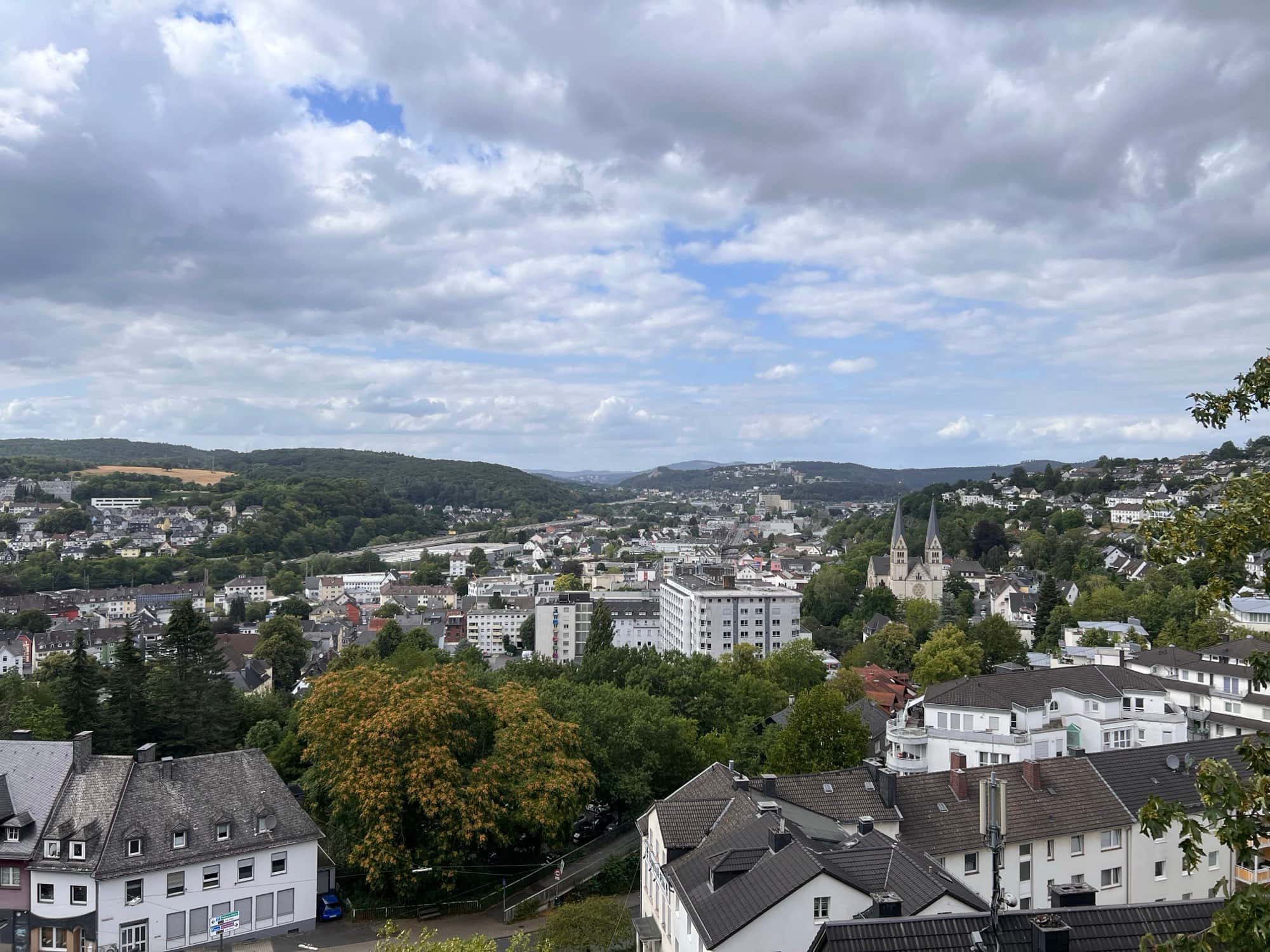 Blick über die Dächer von Siegen mit Kirchtürmen und den bewaldeten Hügeln des Siegerlands